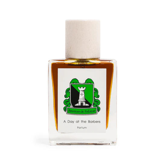 A bottle of "A Day at the Barbers" parfum by Aromas de Salazar with a green and white label and a white cap, exuding a luxurious scent reminiscent of a traditional barbershop experience.