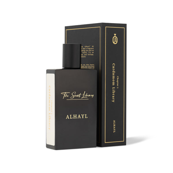 A black rectangular perfume bottle labeled "Alhayl" and "The Scent Library" is placed in front of a matching black and gold box that reads "Alhayl" and "The Scent Library." The fragrance boasts a captivating Woody-Ambery essence with a hint of cardamom.