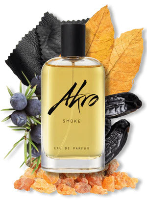 A bottle of Akro SMOKE Eau de Parfum, an aromatic unisex fragrance, is surrounded by various ingredients including leaves, spices, and dark beans.