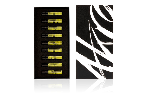 The AKRO 9 x 2ml Discovery Kit by Akro is a sleek black box adorned with an abstract white design and contains nine yellow liquid-filled vials in separate compartments. These vials capture various addictive scents transformed into provocative perfumes, offering an experience of transgressive fragrances that tantalize the senses.