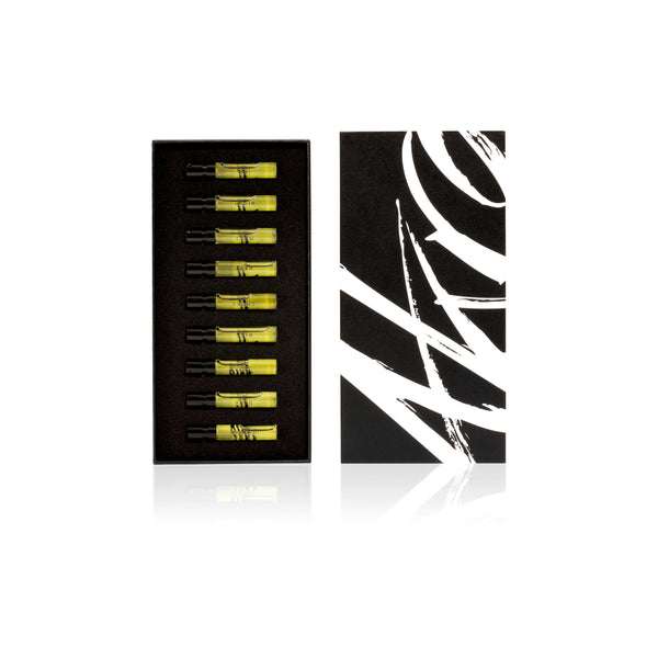 The AKRO 9 x 2ml Discovery Kit by Akro is a sleek black box adorned with an abstract white design and contains nine yellow liquid-filled vials in separate compartments. These vials capture various addictive scents transformed into provocative perfumes, offering an experience of transgressive fragrances that tantalize the senses.