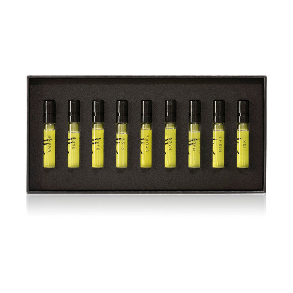 The AKRO 9 x 2ml Discovery Kit by Akro features nine perfume sample vials, labeled: HAZE, DARK, BAR, RISE, SMOKE, HALF, MALT, NIGHT, and INK. These indulgent scents are arranged neatly in a black rectangular box.