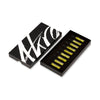 The AKRO 9 x 2ml Discovery Kit by Akro is depicted as a black box adorned with white abstract designs. Its lid is partially open, displaying ten small vials of yellow liquid neatly arranged inside—each one a testament to addictive excess.