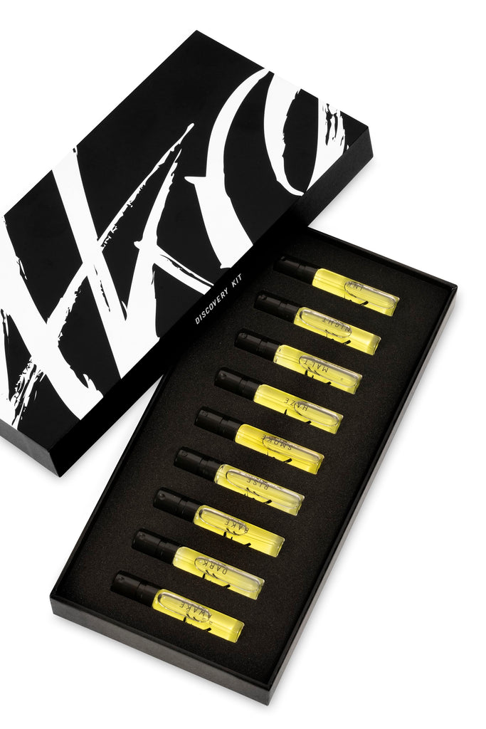 A black box labeled "AKRO 9 x 2ml Discovery Kit" from the brand Akro contains nine small, transparent vials of yellow liquid, each a testament to addictive excess, meticulously arranged in a black foam insert.