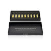 An open black box from the AKRO 9 x 2ml Discovery Kit by Akro reveals a collection of nine small vials filled with yellow liquid, neatly organized in a foam insert. The lid of the box features various words such as "passion," "chocolate," and "caffeine." These bold fragrances turn addictions into perfumes, promising an enticing olfactory experience.