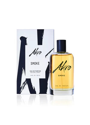 A bottle of Akro SMOKE aromatic eau de parfum with a black cap is placed next to its white packaging box featuring bold black lettering.
