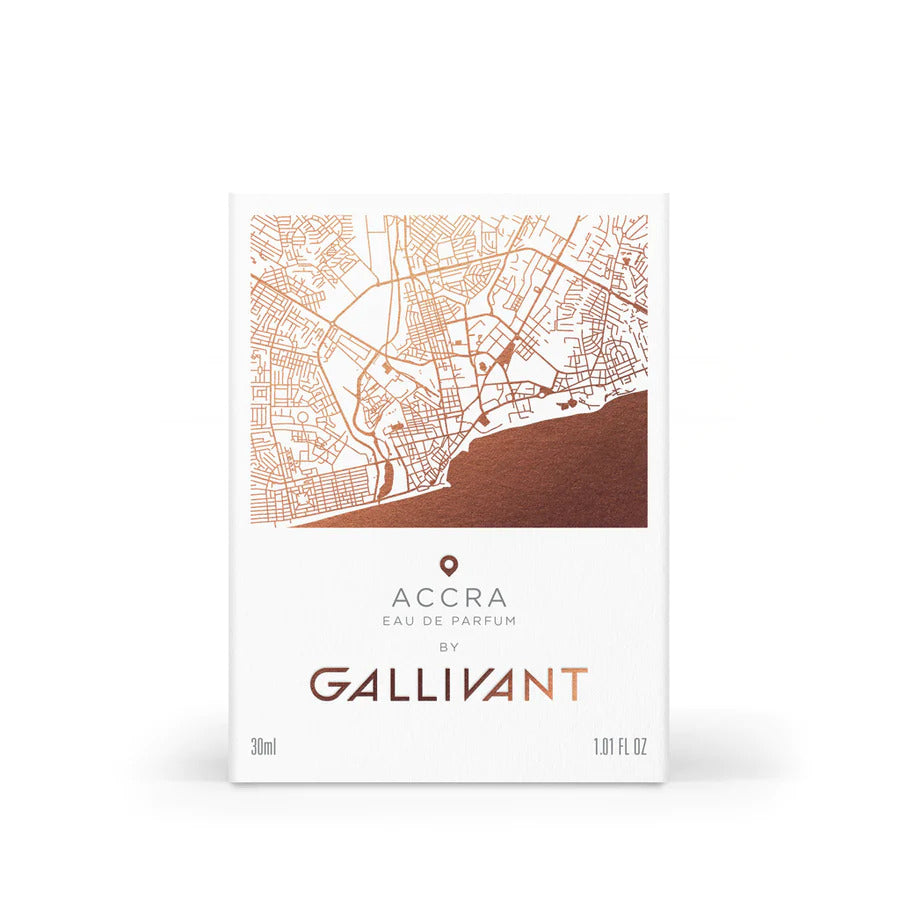 A white perfume box labeled "Accra EAU DE PARFUM by Gallivant Perfumes" features a detailed map design in copper tones. The box, with a 30 ml (1.01 FL OZ) capacity, hints at exotic scents like tropical mango and papaya intertwined with the fiery notes of hot peppers.