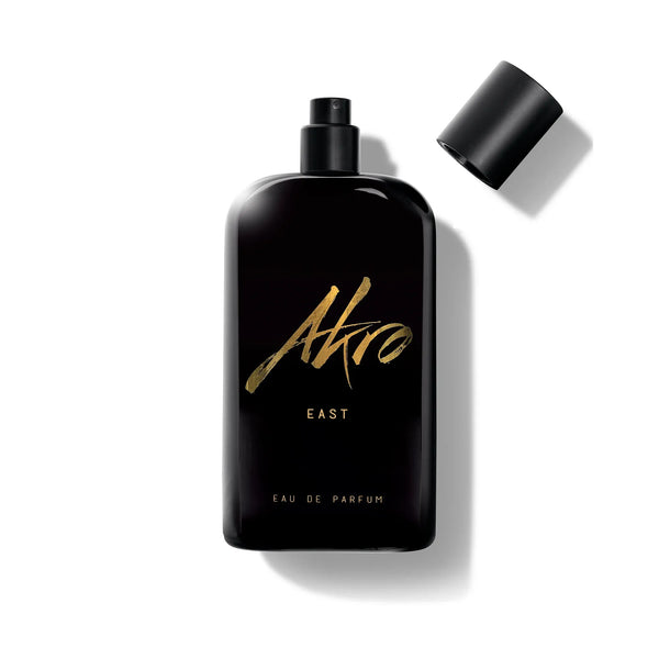 A black perfume bottle labeled "East" by Akro evokes the essence of Oud from the Middle East, with "Eau de Parfum" inscribed at the bottom. The cap is off and placed to the right.