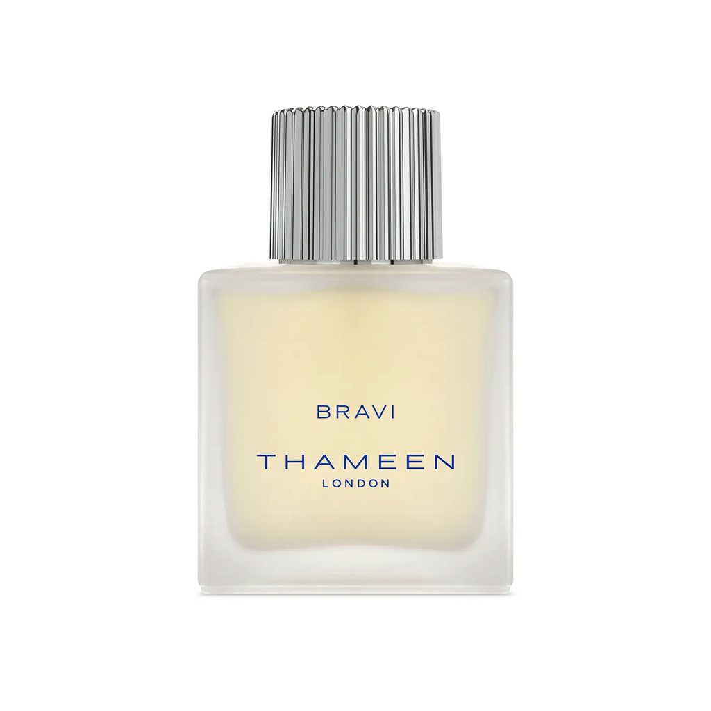 A square, frosted glass bottle of THAMEEN Bravi Cologne Elixir with a silver ribbed cap and blue text, capturing the allure of intoxicating tuberose.