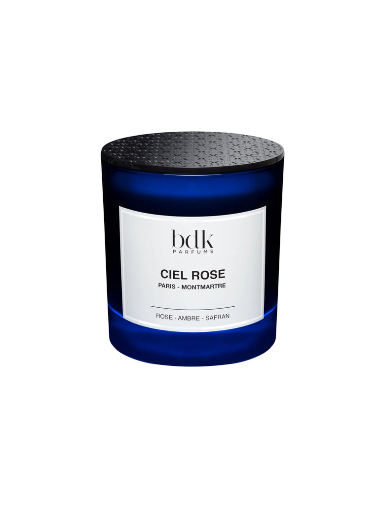 A blue candle jar labeled "Ciel Rose BDK Parfums Paris - Montmartre" with notes of fresh rose, amber, and saffron accord.