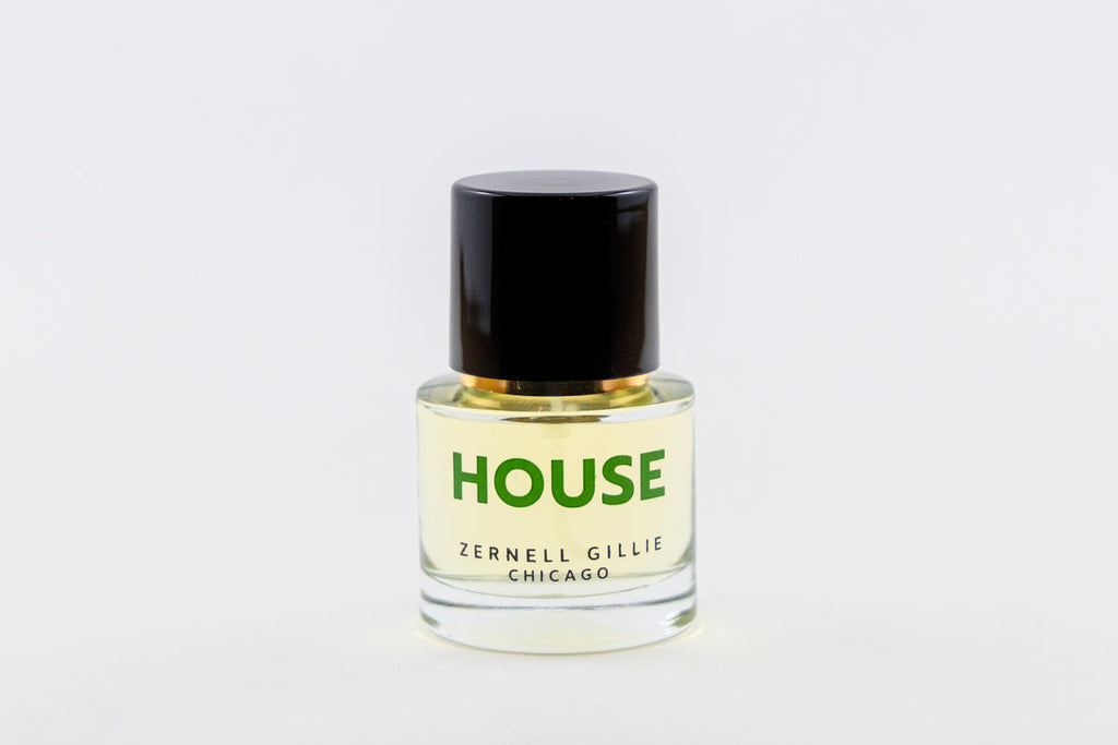 A small glass bottle with a black cap, labeled "HOUSE" in green, and "Zernell Gillie" in black. This unisex fragrance captures the essence of house music, creating a signature scent that resonates with both energy and elegance.