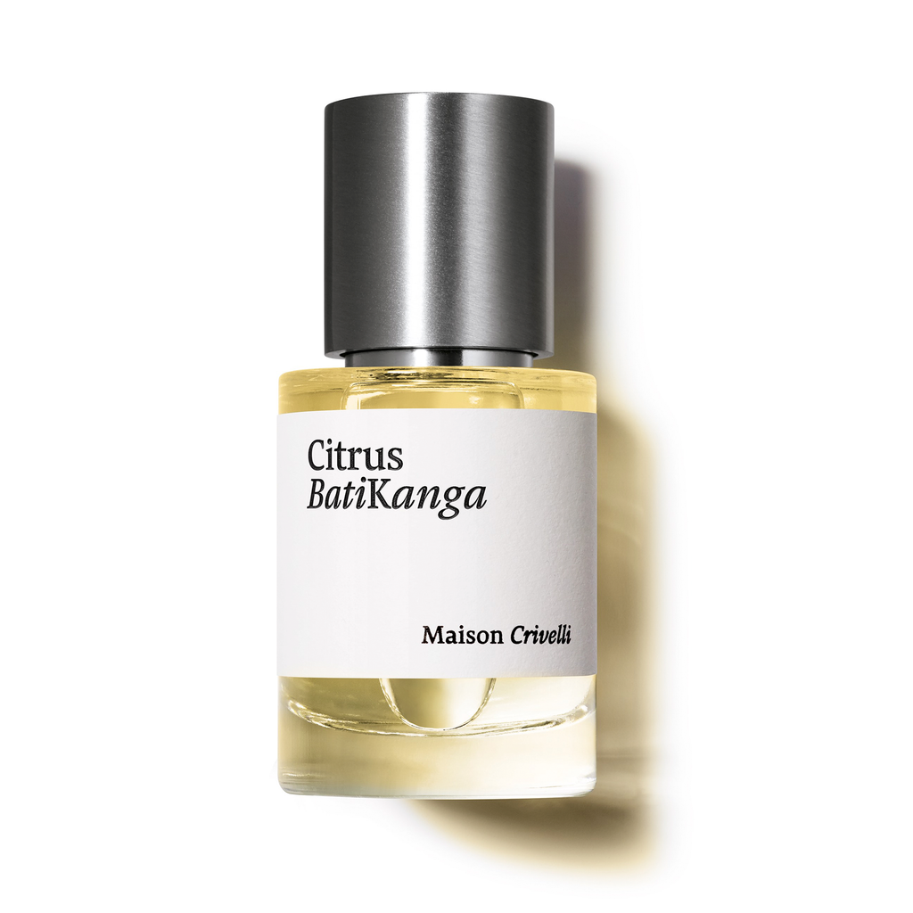 A bottle of Citrus Batikanga perfume by Maison Crivelli, showcasing its bergamot essential oil notes, is displayed against a white background. The bottle is adorned with a silver cap and features a white label.