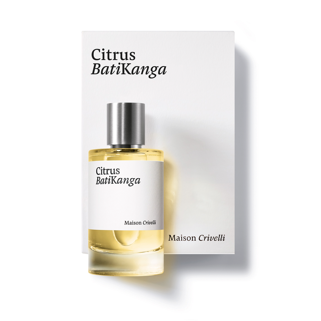 A bottle of "Citrus Batikanga" perfume by Maison Crivelli, showcasing the vibrant freshness of bergamot essential oil, stands in front of its box with corresponding text and design.