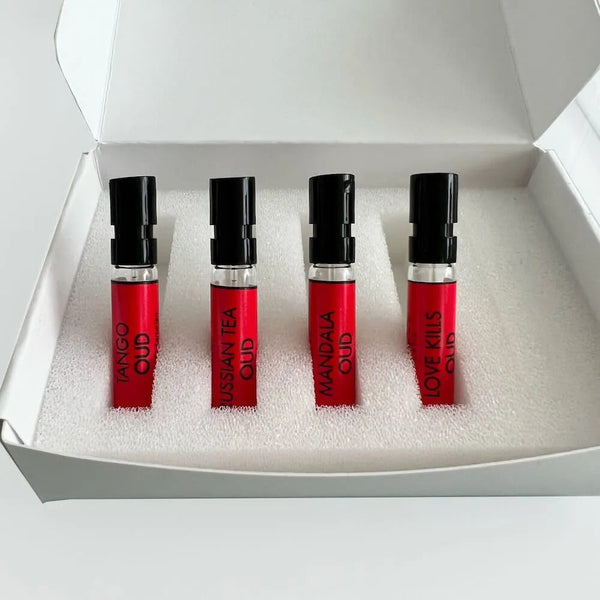 The Masque Milano Ruby Collection Discovery Set from the prestigious brand Masque Milano features a sleek white box containing four small spray bottles with red labels. Each bottle is distinctively labeled as "Tango Oud," "Russian Tea Oud," "Mandala Oud," and "Love Kills Oud." This carefully curated set provides an opulent introduction to their finest oud fragrances.