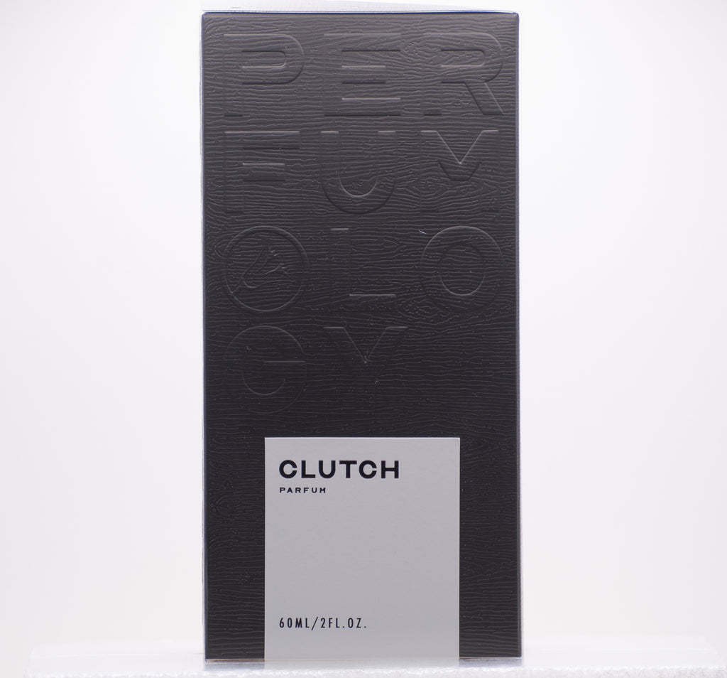 A black box with embossed text "Perfumology." A smaller, white label on the front reads "Clutch, 60ML/2FL.OZ." This independent perfume offers an exhilarating scent, featuring a sophisticated leather fragrance.