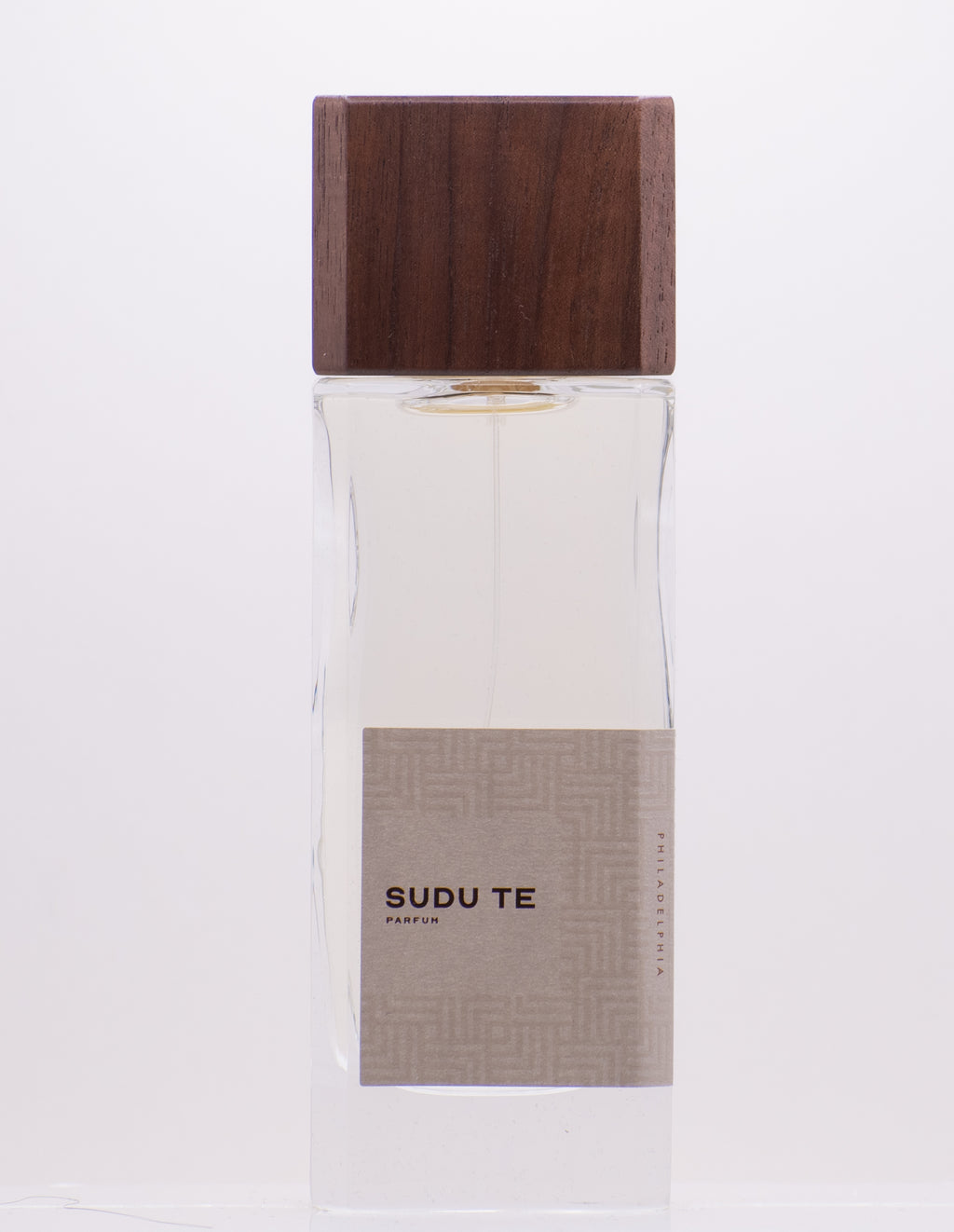 A rectangular glass perfume bottle with a coconut wood cap, labeled "Sudu Te" by Perfumology. The label is beige with subtle geometric patterns.