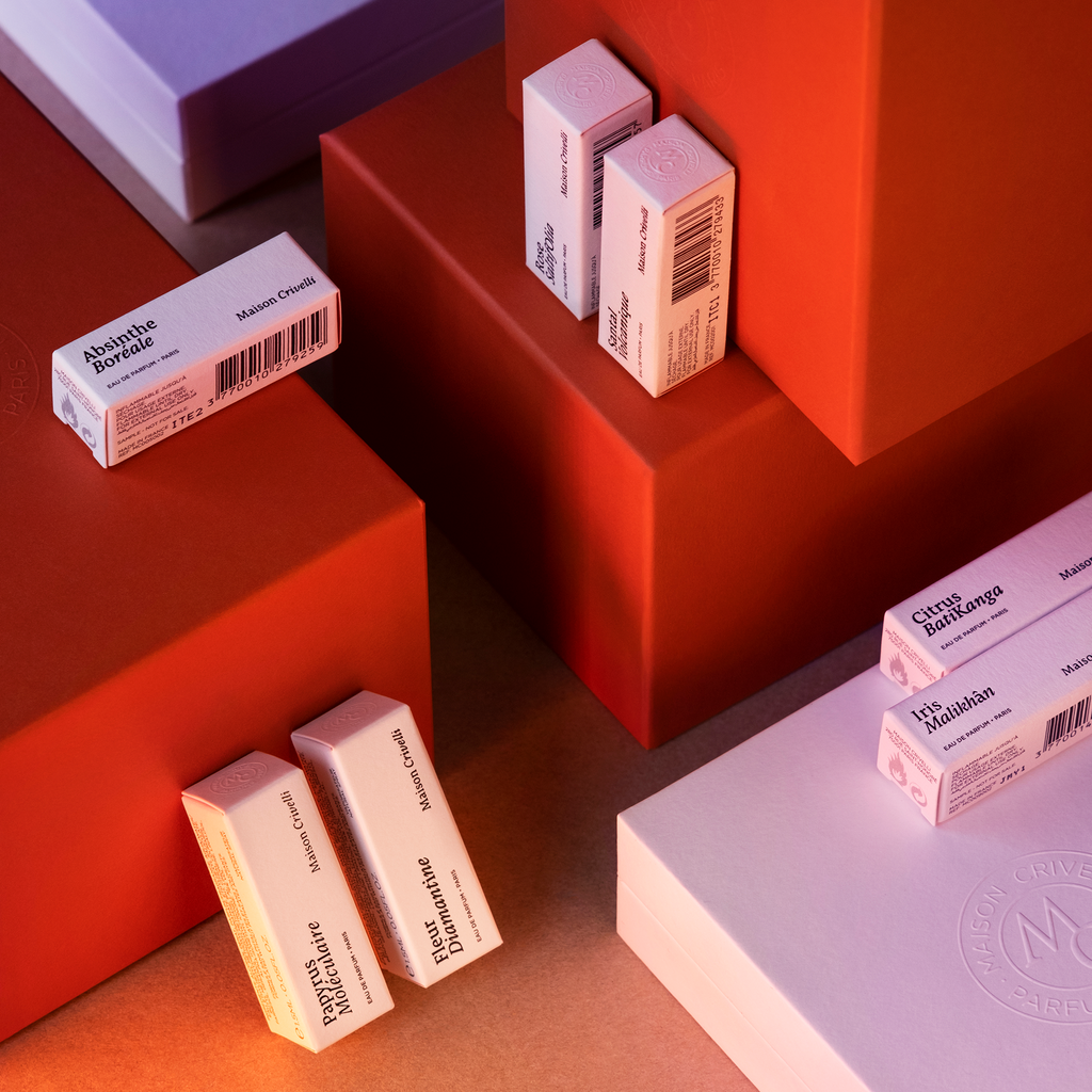 Maison Crivelli Discovery Set, featuring ten 1.5ml vials, each embodying a unique olfactory signature, is displayed on and around large red and white rectangular platforms.