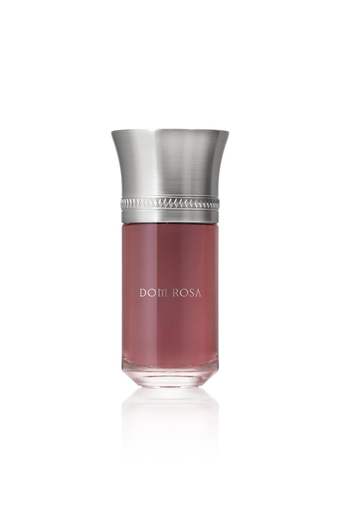 A bottle of Dom Rosa by Liquides Imaginaires, designed by Sonia Constant, features a metallic silver cap and pink liquid inside, displayed on a white background. This Amber Floral fragrance exudes elegance and sophistication.