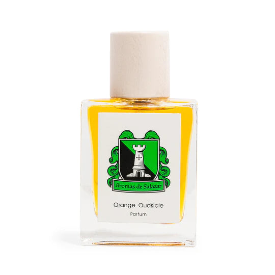 The "Orange Oudsicle" perfume by Aromas de Salazar features a bottle adorned with a white cap and a green and black label showcasing a tower. Inside, the creamy orange fragrance is enriched with notes of Cambodian oud for an exotic experience.