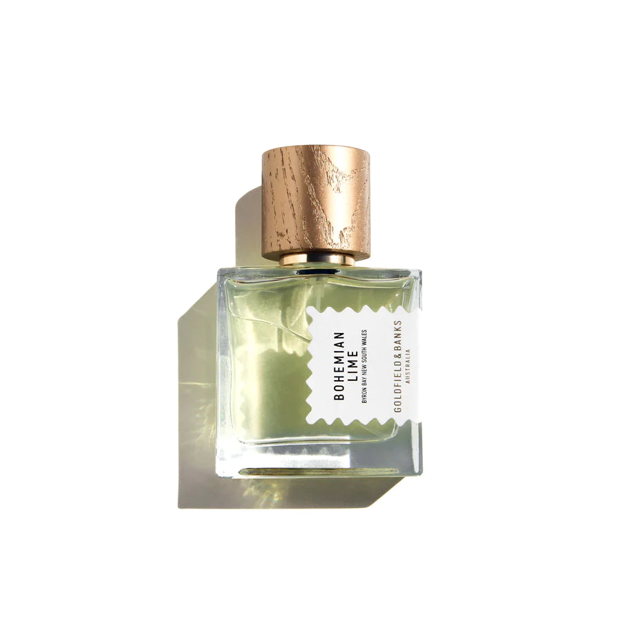 A glass perfume bottle with a wooden cap, labeled "Bohemian Lime" by Goldfield & Banks. The bottle is filled with a light green liquid that hints at the tropical fragrance of Australian finger lime, and is photographed against a white background.