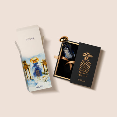 A blue perfume bottle with a gold cap is displayed partially out of its black and gold box, promising an olfactory journey. Another colorful box with an image of the Granada Sapphire Collection by Widian stands nearby, hinting at the luxury scent within.