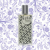 A clear glass perfume bottle named "Hush Hush" with a silver cap, branded "4160Tuesdays," set against a purple floral-patterned background, exudes a hint of ethyl vanillin.