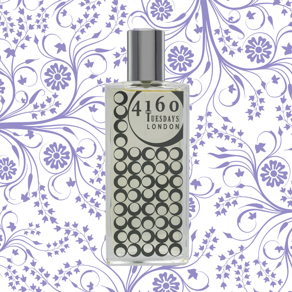 A clear glass perfume bottle named "Hush Hush" with a silver cap, branded "4160Tuesdays," set against a purple floral-patterned background, exudes a hint of ethyl vanillin.