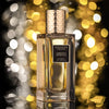 A glass bottle of Ambrosia Imperiale by Navitus Parfums, featuring a metallic, textured cap, is displayed against a blurred, sparkling background with a subtle hint of banana note in its aroma.