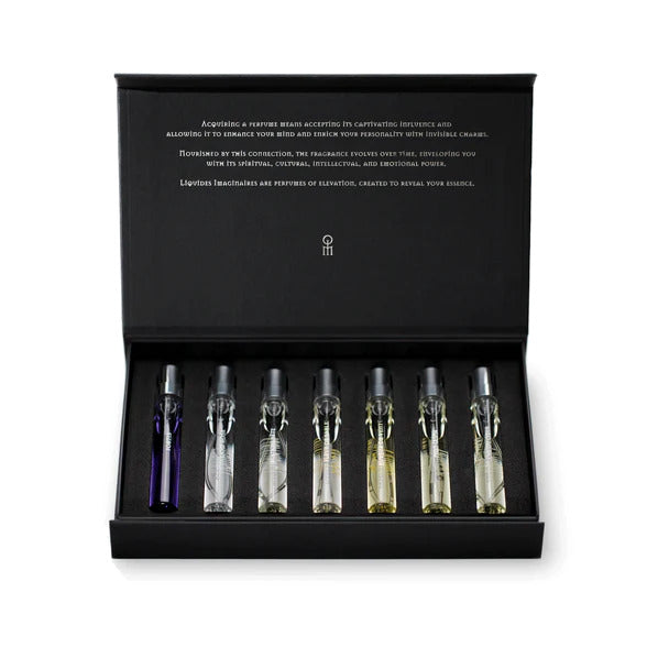 The Seven Charms 7 x 7.5ml Set by Liquides Imaginaires is a black box containing seven small perfume vials with varied colored liquids, neatly arranged in a row – perfect for fragrance lovers.