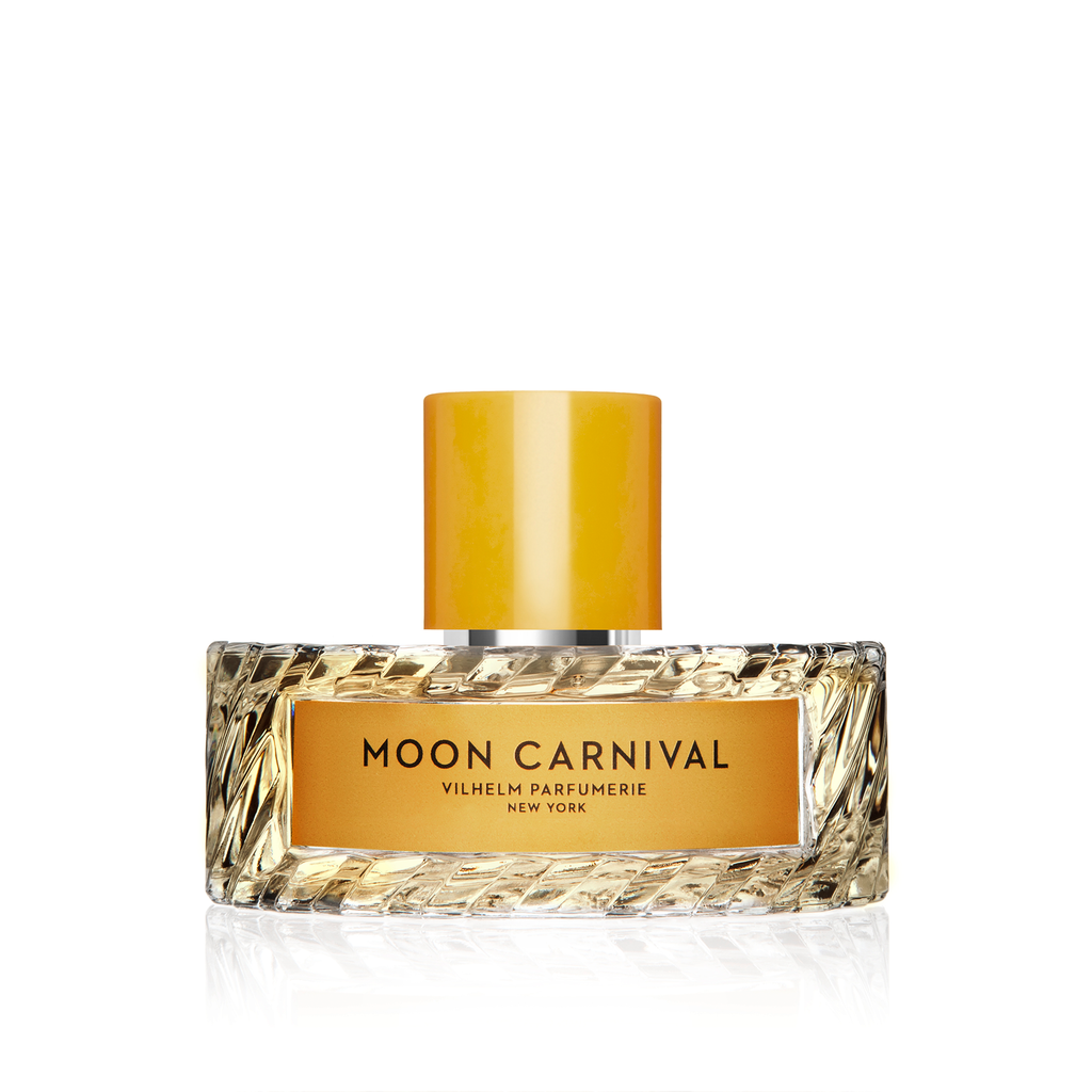 A clear glass bottle labeled "Moon Carnival" by Vilhelm Parfumerie, adorned with a gold cap and intricate base texture. The fragrance offers enticing whispers of tuberose, creating an alluring essence.