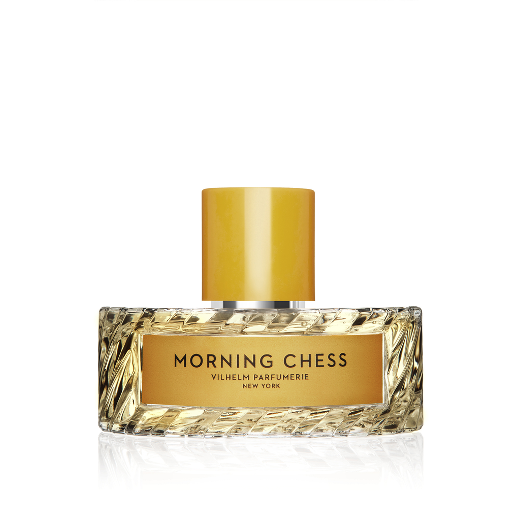 A clear, intricately textured bottle of Vilhelm Parfumerie's Morning Chess perfume features a golden label and cap, exuding notes of bergamot and Tuscan leather.