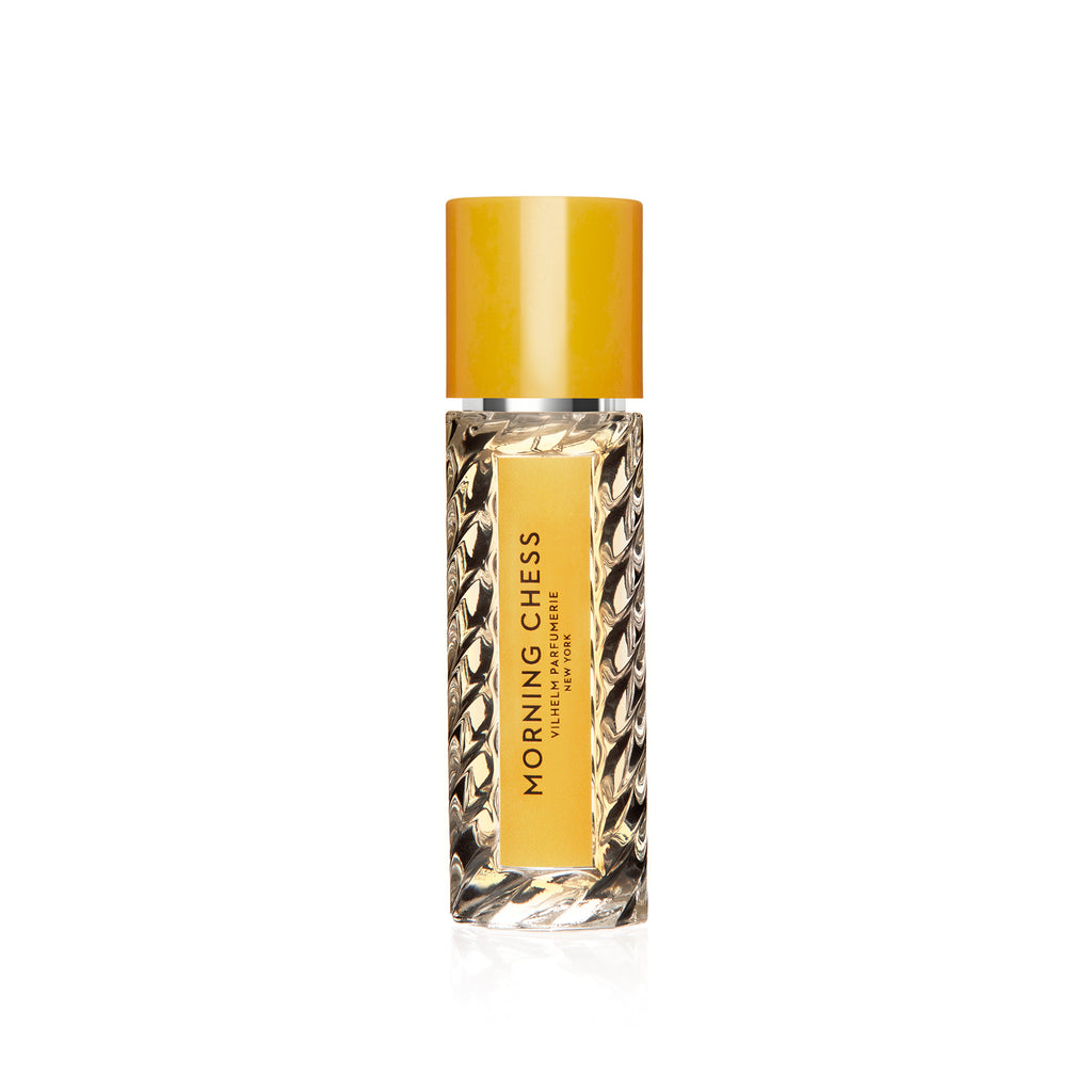 A bottle of Vilhelm Parfumerie's "Morning Chess" perfume, featuring a textured glass design, yellow cap, and a yellow label, infused with notes of patchouli.
