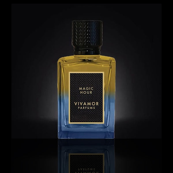 A bottle of Magic Hour by VIVAMOR Parfums, displaying its yellow and blue gradient design, exudes exotic sophistication against a dark background.