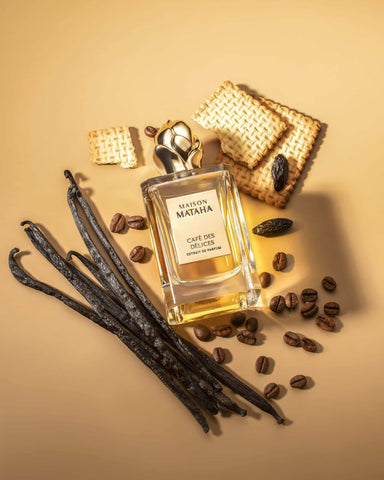 Perfume bottle with gold cap and amber liquid with vanilla wafer and coffee beans