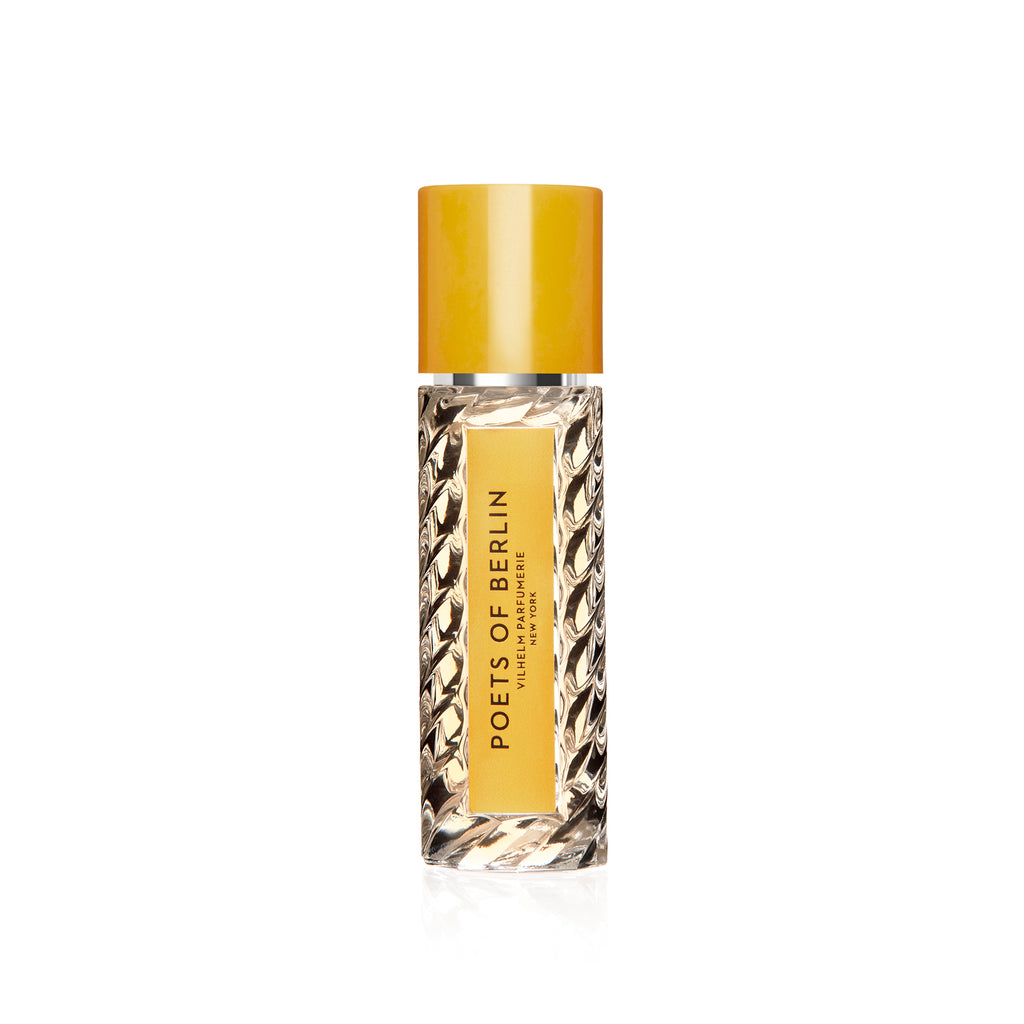 A clear glass bottle of perfume labeled "Poets of Berlin" by Vilhelm Parfumerie with a yellow cap and an ornate design, hinting at notes of lemon and vetiver.