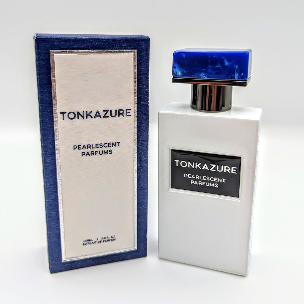 A white bottle of Pearlescent Parfums' Tonkazure with a blue cap sits elegantly next to its matching blue and white box, evoking hints of tonka bean.