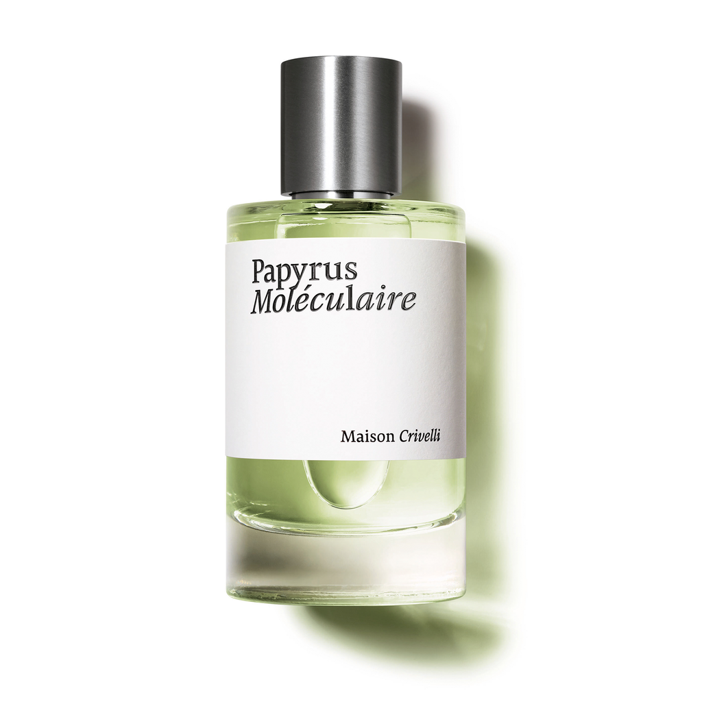 A bottle of Maison Crivelli's Papyrus Moléculaire perfume, adorned with a metallic cap and a white label showcasing the perfume's name, contains light green liquid enriched with papyrus essential oil and casts a delicate shadow.