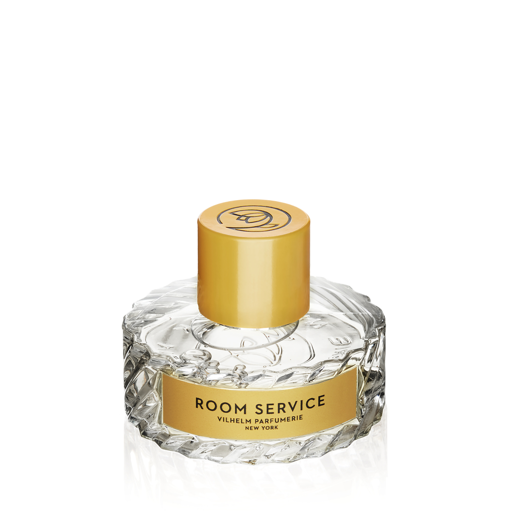 A glass perfume bottle with a gold cap and gold label, inscribed with "Room Service Vilhelm Parfumerie," exudes the elegance of luxury bath experiences, reminiscent of flower petals floating in enchanted waters.