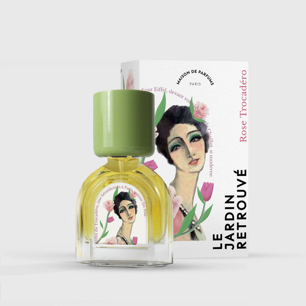 A bottle of Le Jardin Retrouvé's Rose Trocadéro floral Eau de Parfum with a green cap is placed in front of its white box, which features a woman's portrait and tulip illustrations.