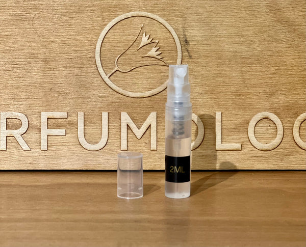Wooden display with small perfume vials, spray bottle, and circular emblem