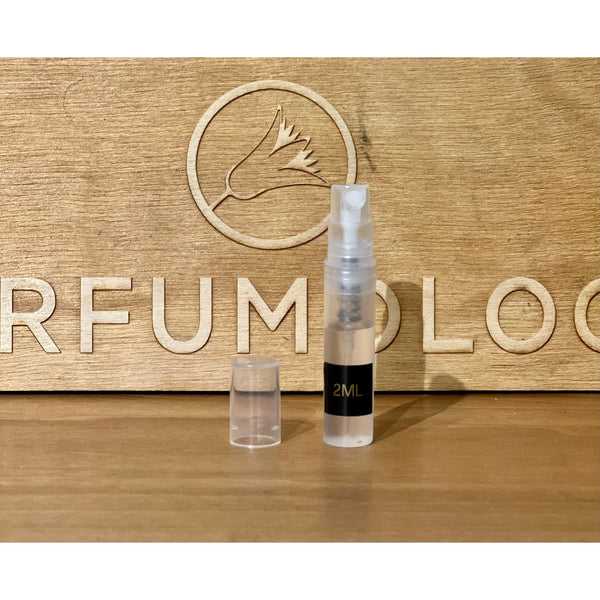 A 2ml spray bottle with a clear cap is placed on a wooden surface. The background, engraved with the "PERFUMOLOG" logo, hints at the Extra Sexiest Scent on the Planet Ever (IMHO) by 4160Tuesdays for your next date night.