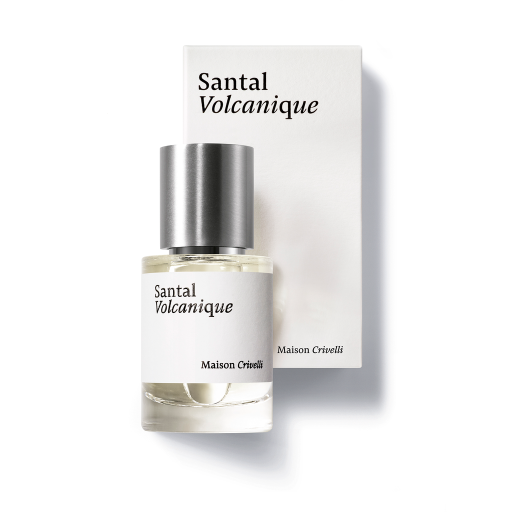 A bottle of Santal Volcanique by Maison Crivelli, with its woody, spicy, and musky notes, sits elegantly next to its chic white and black packaging.