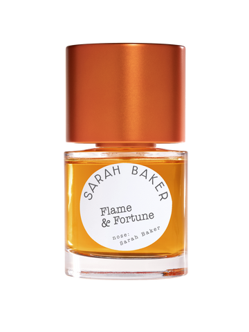 A bottle of "Flame & Fortune" perfume by Sarah Baker, featuring an amber liquid inside, a bronze cap, and a subtle hint of tuberose essence.
