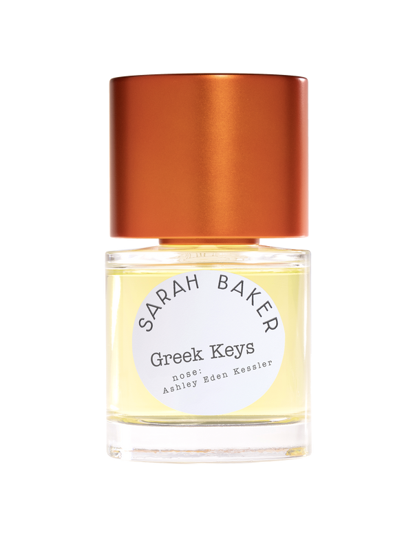 A bottle of Sarah Baker's "Greek Keys" perfume featuring a gold cap and light yellow liquid, evoking a touch of citrus freshness.