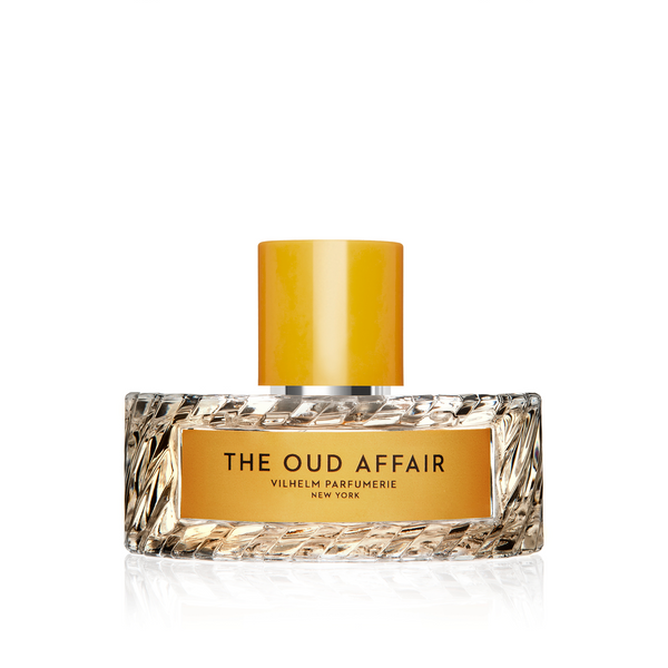 A clear, rectangular perfume bottle with a yellow cap, labeled "The Oud Affair, Vilhelm Parfumerie," evokes sophistication with hints of wild honey.