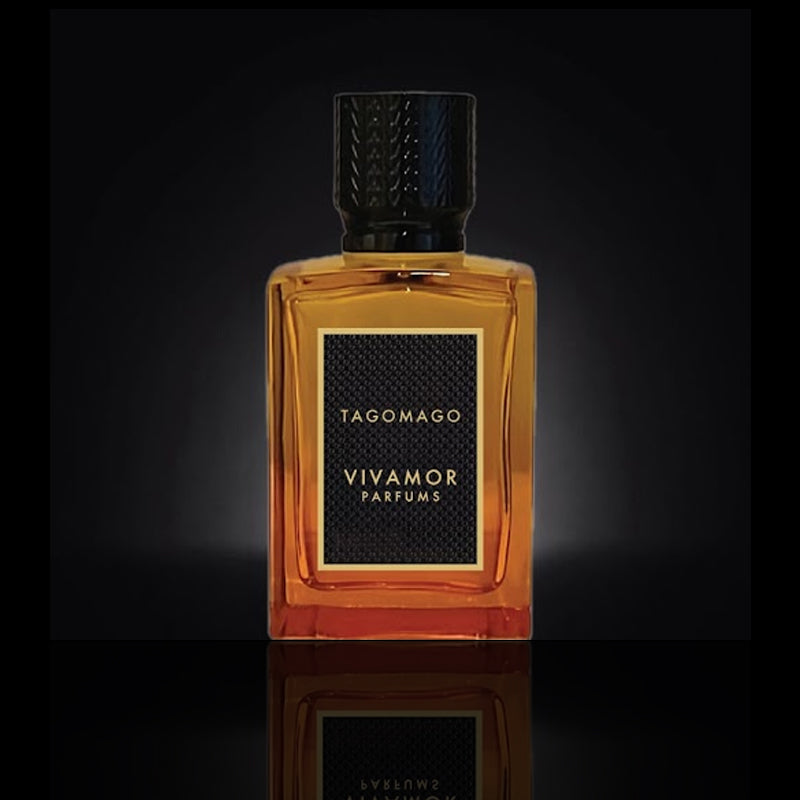 A rectangular amber-colored perfume bottle labeled "Tagomago" by VIVAMOR Parfums, renowned for its tropical fragrance, with a black cap set against a dark background.