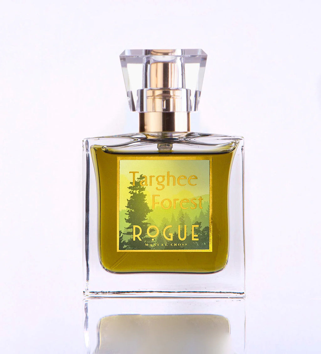 A clear glass bottle of Targhee Forest Rogue Perfumery Eau de Parfum with a gold cap, containing greenish-yellow liquid and a label featuring a woody forest design.