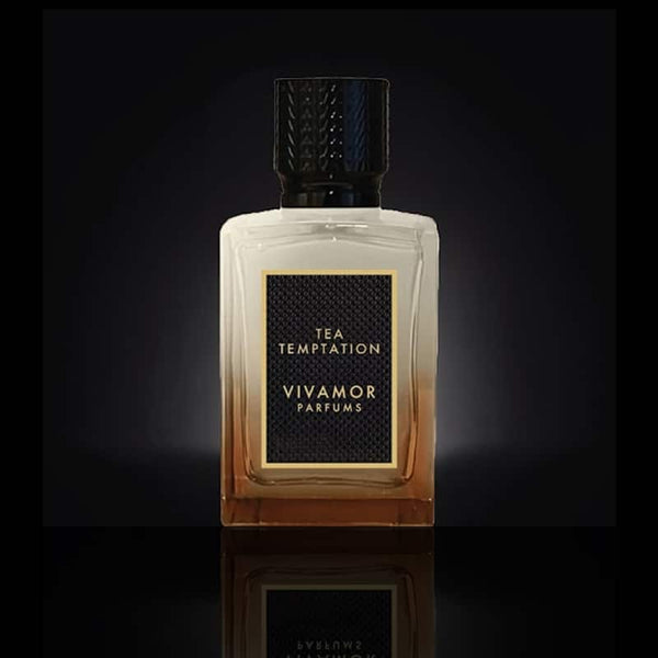 A bottle of "Tea Temptation" Extrait de Parfum by VIVAMOR Parfums, showcasing a black cap and gradient glass design set against a dark background, evokes the sophisticated allure of Darjeeling Earl Grey tea.