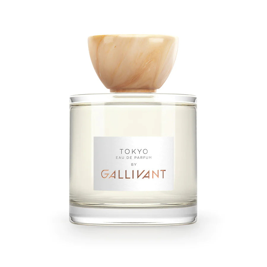 A clear glass bottle of Tokyo by Gallivant from Gallivant Perfumes, featuring a beige marbled cap, white label, and gold text, offering a zingy spicy woody fragrance.