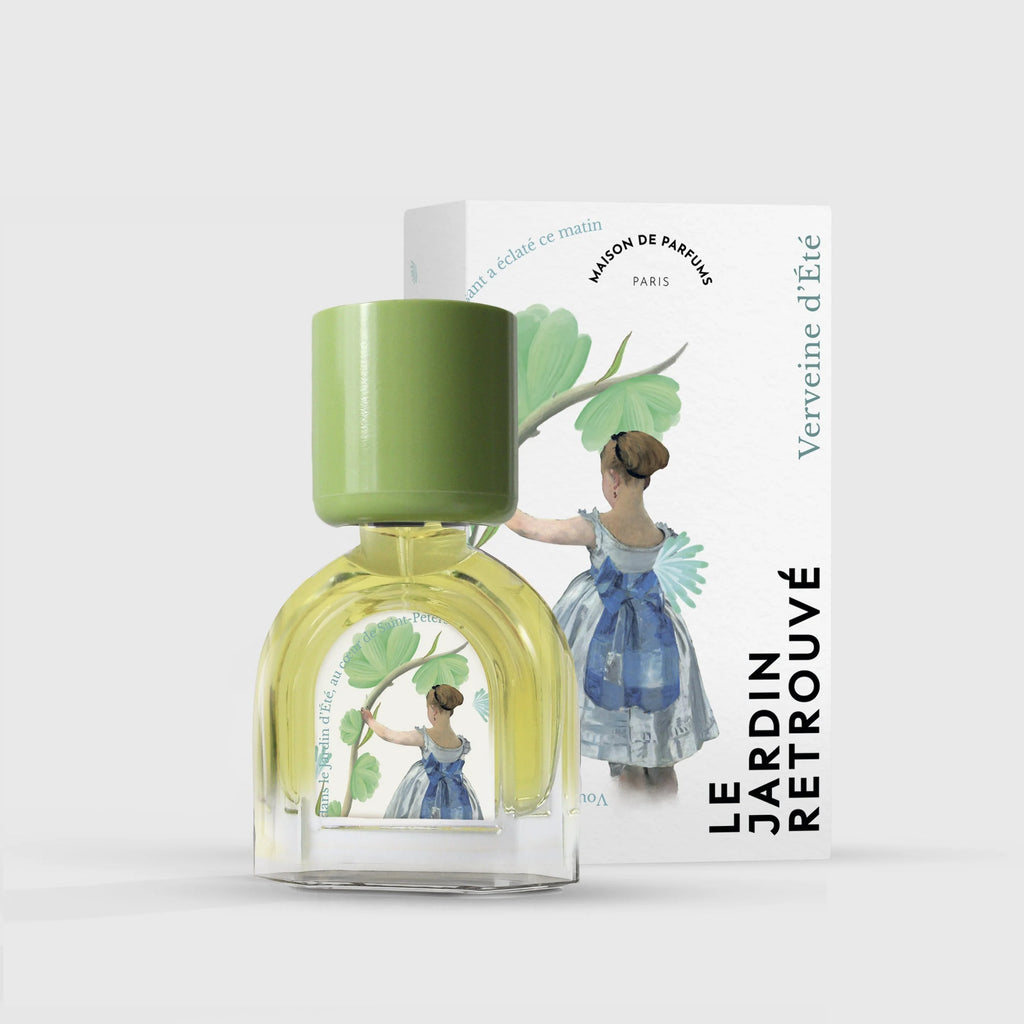 A glass bottle of Verveine d'Eté with a green cap placed in front of its box. The box and bottle feature an illustration of a woman in a blue dress reaching up to a green plant. Text reads "Le Jardin Retrouvé." Experience the fresh scent that captures the essence of summer.